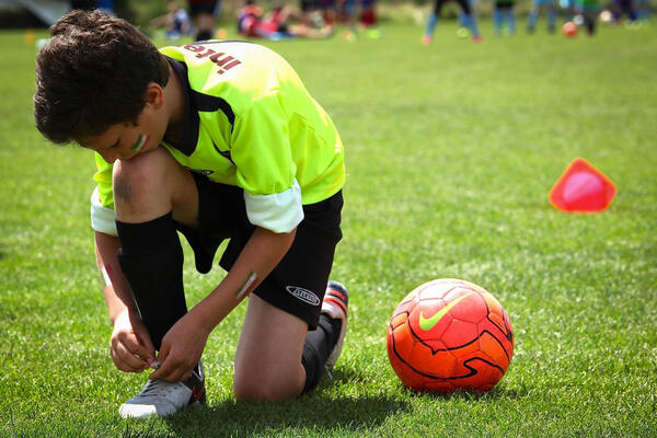 Bild vergrößern: Junge mit Fußball auf dem Rasen