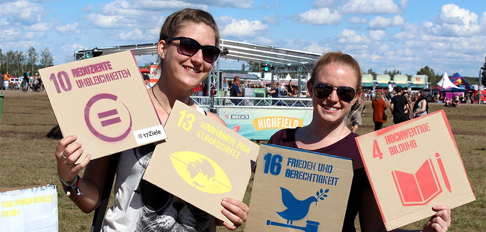 Bild vergrößern: Zwei junge Frauen mit Tafeln zu Nachhaltigkeitszielen