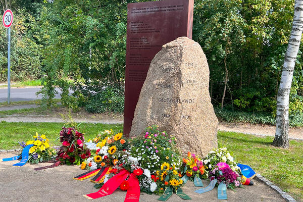 Blumengeschmückte Gedenkststelle für die Maueropfer am Adam-Kuckhoff-Platz