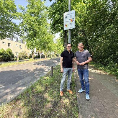 Bild vergr&ouml;&szlig;ern: Bilderserie St&auml;dtepartnerschaftsbesuch 2026: Delegation Schopfheim und Landkreis Swidnica in Kleinmachnow; hier: B&uuml;rgermeister Bodo Krause (li) und Dirk Harscher (re) vor dem St&auml;dtepartnerschaftsschild am Ortseingang Thomas-M&uuml;ntzer-Damm
