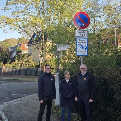 Bild vergr&ouml;&szlig;ern: Das Foto zeigt B&uuml;rgermeister Bodo Krause, Eigenherd-Schule-Leiterin Karen Korge und Karsten Schulze vom ADAC Berlin-Brandenburg vor dem neuen Elternhaltestellen-Schild