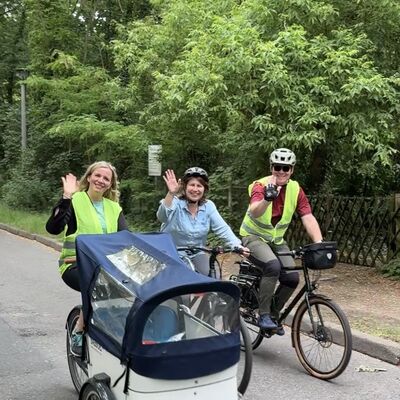 Bild vergr&ouml;&szlig;ern: Das Foto zeigt drei winkende Radler, die bei der Auftaktour des Stadtradelns 2026 kr&auml;ftig in die Pedale treten