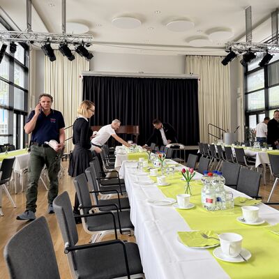 Bild vergr&ouml;&szlig;ern: Das Foto zeigt Besch&auml;ftigte des Rathauses beim Eindecken der Tische f&uuml;r die nachgeholte Seniorenweihnachtsfeier im Juni 2026 im B&uuml;rgersaal