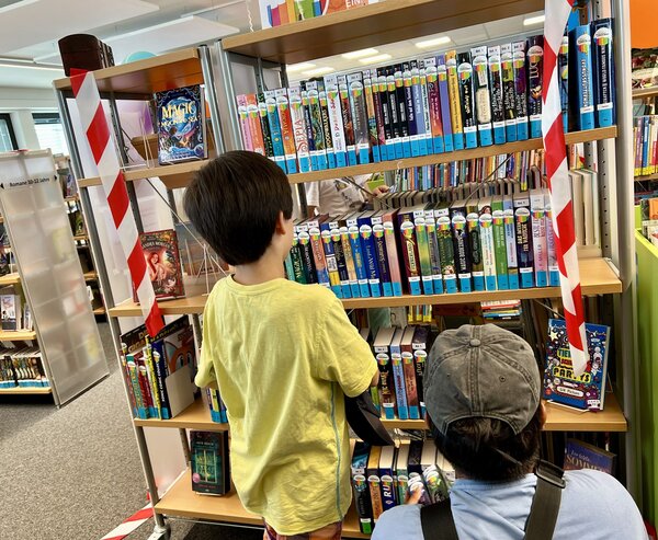 Bild vergr&ouml;&szlig;ern: Das Foto zeigt zwei Kinder, die in der Bibliothek Kleinmachnow vor einem B�cherregal stehen