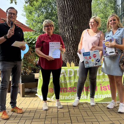 Bild vergr&ouml;&szlig;ern: Das Foto zeigt folgende Situation: Siegerehrung STADTRADELN 2026: B&uuml;rgermeister Bodo Krause (li.), Fachdienstleiterin Susanne Gasch (2.v.re.) und Rathaus-Mitarbeiterin Emily Reich (re.) gratulieren der Kita Waldh&auml;uschen (708 km) zum tollen Erfolg