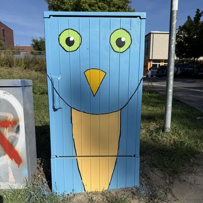Bild vergr&ouml;&szlig;ern: Das Foto zeigt einen von Sch&uuml;lerinnen und Sch&uuml;lern der Klasse 6a der Grundschule Auf dem Seeberg gestalteten Stromkasten mit einem blauen Vogel mit gr&uuml;nen Augen