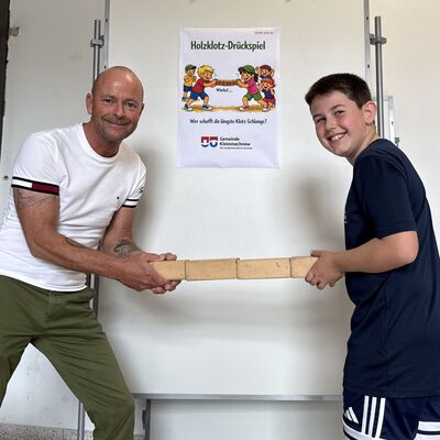 Bild vergr&ouml;&szlig;ern: Das Foto zeigt einen Mann und einen Jungen beim Holzklotz-Dr&uuml;ckspiel beim Sportlichern Aktionstag rund ums Rathaus am 5. September 2026