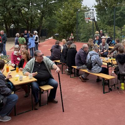 Bild vergr&ouml;&szlig;ern: Das Foto zeigt Menschen, die bei Kuchen, Kaffee und Limo den WCD 2026 nach getaner Arbeit gem&uuml;tlich auf dem Schulhof der Grundschule Auf dem Seeberg und des Hortes Hochwald ausklingen lassen.