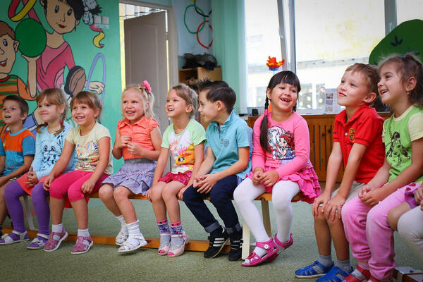 Bild vergrößern: Kindergartenkinder auf einer Bank im Kindergarten