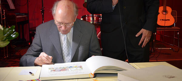 Bild vergr&ouml;&szlig;ern: Pfarrer Reinald Elliger tr&auml;gt sich ins Goldene Buch der Gemeinde Kleinmachnow ein. Neben ihm B&uuml;rgermeister Michael Grubert